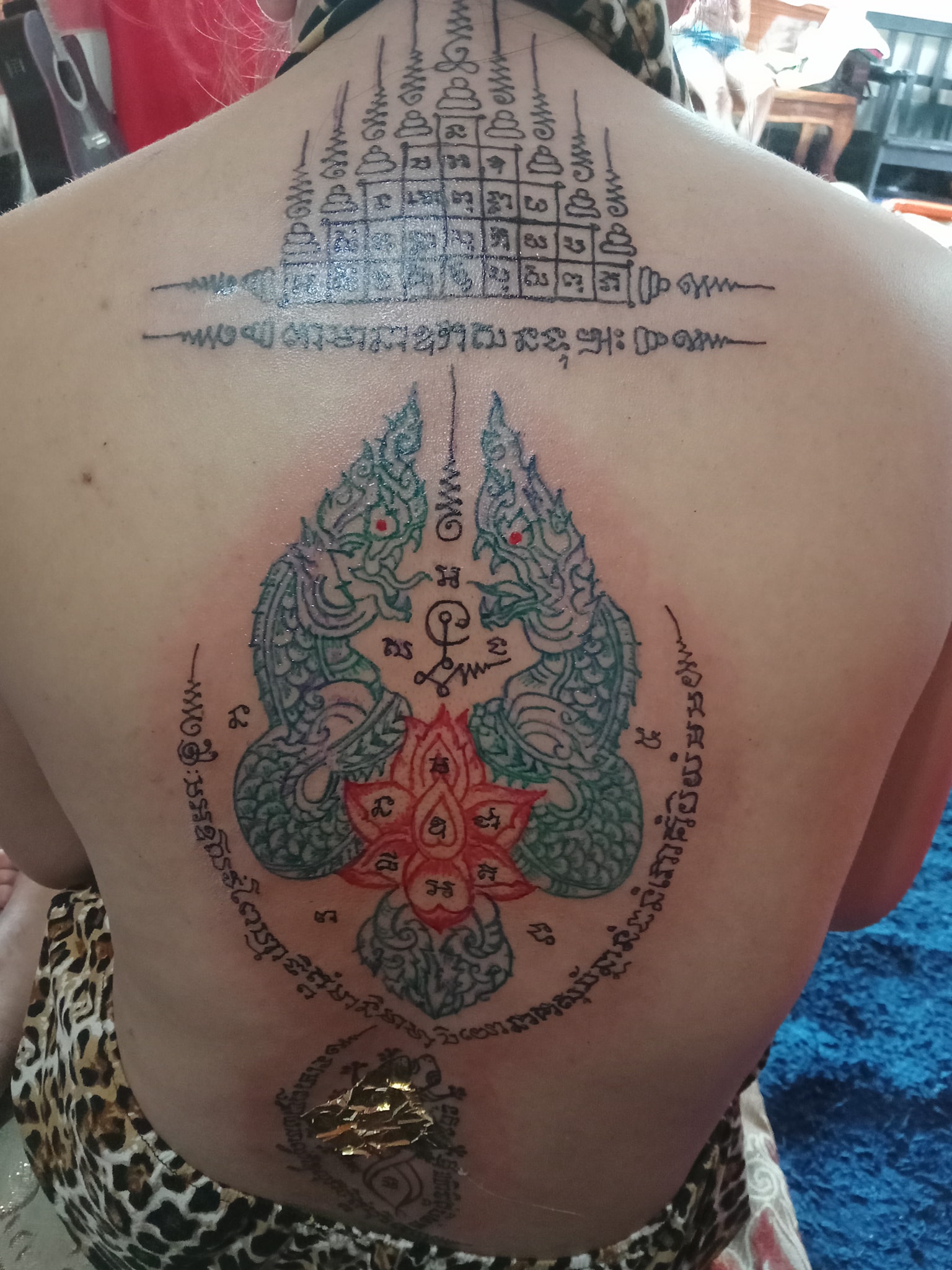 Sacred script tattoo placed across the back