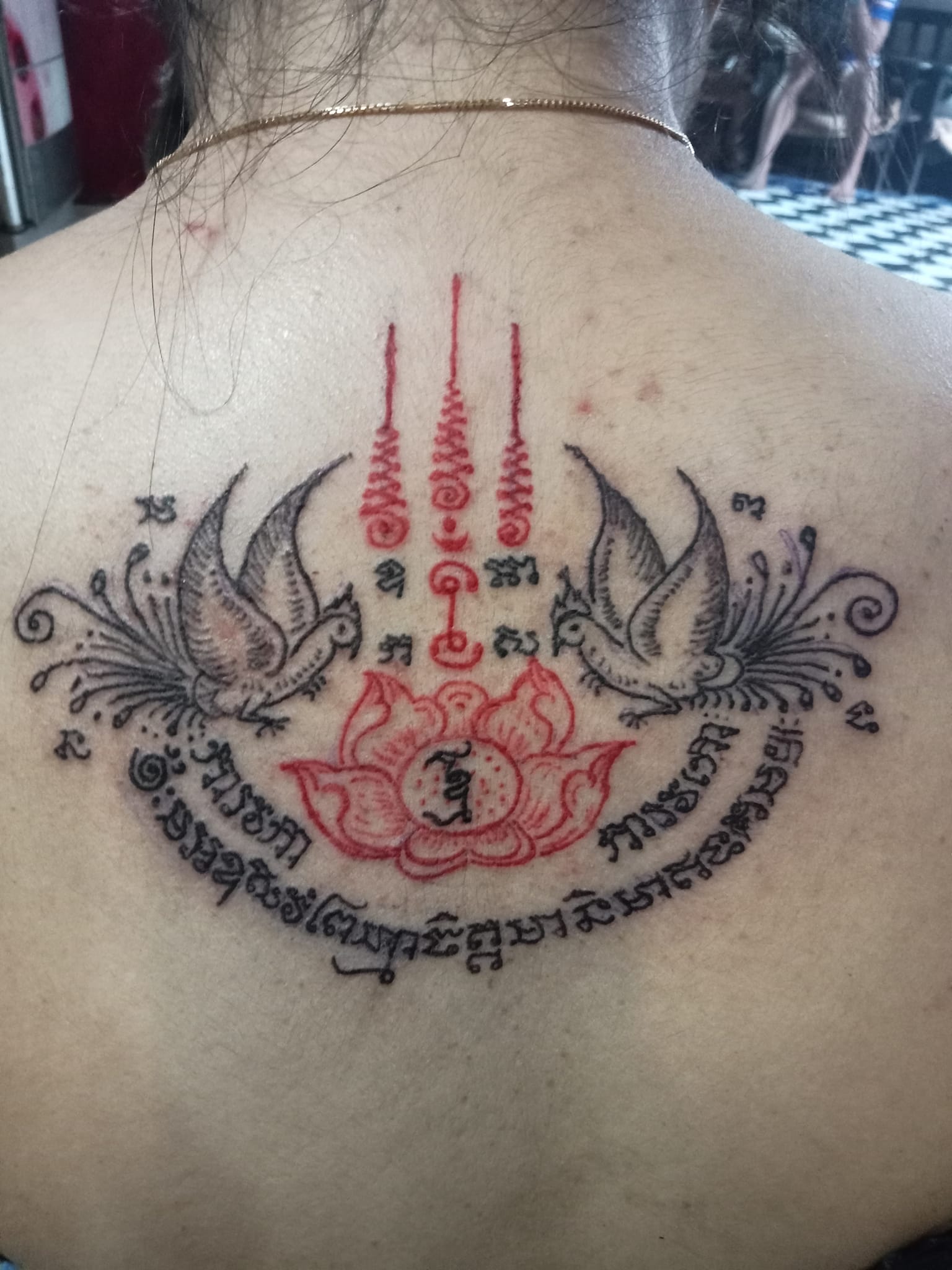 Sacred script tattoo placed across the back